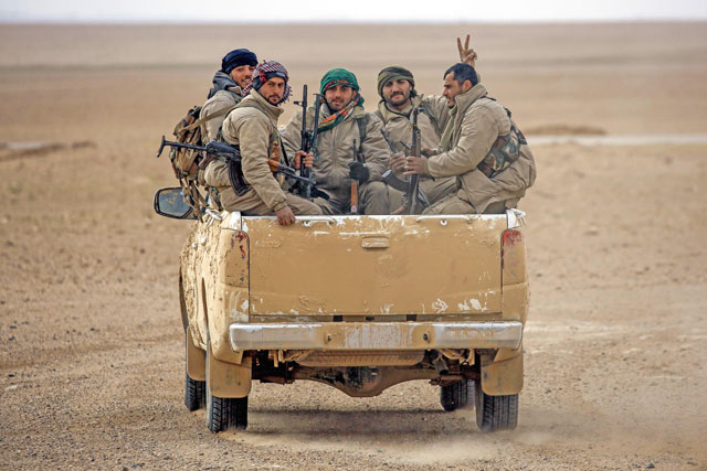 This file photo taken on February 8 shows members of the Syrian Democratic Forces , made up of US-backed Kurdish and Arab fighters, riding in an armoured vehicle near the village of Bir Fawaz, 20km north of Raqqa, Syria (AFP photo)