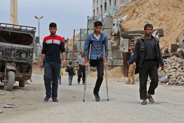 Civilians walk in the former Syrian town of Douma on the outskirts of Damascus, on Tuesday, after the Syrian army declared that all anti-regime forces have left Eastern Ghouta (AFP photo)