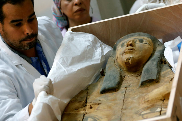 Egyptian antiquities officials uncrate a sarcophagus lid during a ceremony after its repatriation from Israel at the Egyptian Museum in Cairo, on Tuesday (Reuters photo)