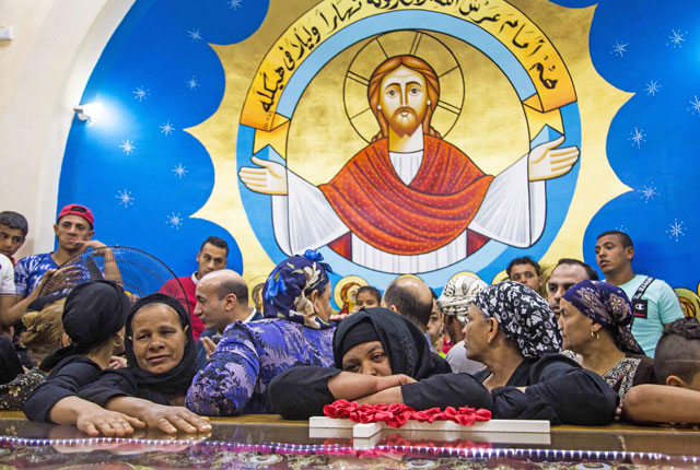 Relatives mourn over the portraits of 20 Egyptian Coptic Christian men who were beheaded by militants on the beach of Sirte in Libya on 2015, during their funereal ceremony in the martyrs church in the village of Al Our in Egypt's southern province of Minya, on Tuesday (AFP photo)
