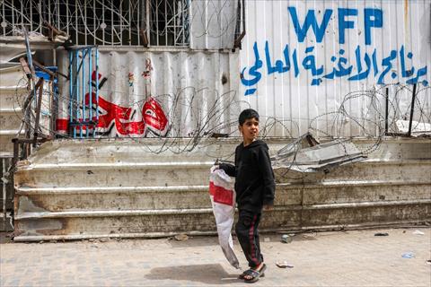 A boy walks with an empty sack past a closed-down bakery that ran out of flour in Gaza City on April 1, 2025 (AFP photo)