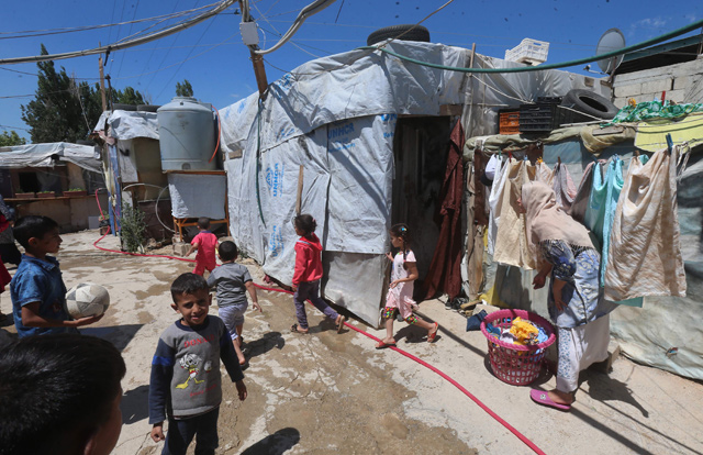 Syrian children play as a woman hangs her washing in the narrow alleys of a refugee camp on the outskirts of the town of Zahle in Lebanon’s Bekaa Valley on June 23 (AFP photo)