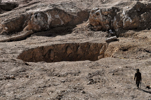 A member of the Hashed Al Shaabi (Popular Mobilisation Unit) paramilitaries walks next to a sinkhole, known as the Khasfah (an Arabic word for a crack or a hole that opens up in the ground), in the village of Athbah, south of Mosul, on Sunday (AFP photo)