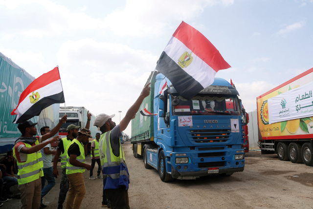 People on the Egyptian side of the Rafah border crossing wave flags as a convoy of lorries carrying humanitarian aid crosses to the Gaza Strip on Saturday (AFP photo)