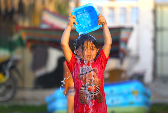 A Palestinian child pours water on his head as temperatures rose at a refugee camp in Rafah, in the southern Gaza Strip, on Thursday (AFP photo)