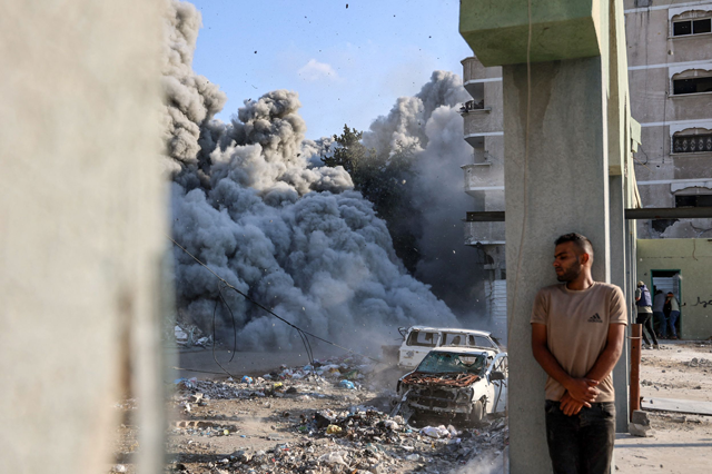 A man takes cover behind a column as an explosion propagates smoke and dust during an Israeli strike which reportedly targeted a school in the Zeitoun district on the outskirts of Gaza City, on September 1, 2024, amid the ongoing Israeli war on the Palestinian territory (AFP photo)