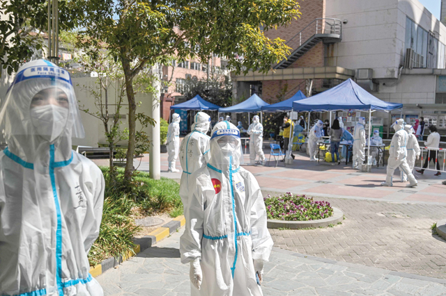 Workers and volunteers look on in a compound where residents are tested for the COVID-19 coronavirus during the second stage of a pandemic lockdown in Jing, a district in Shanghai on Monday (AFP photo)