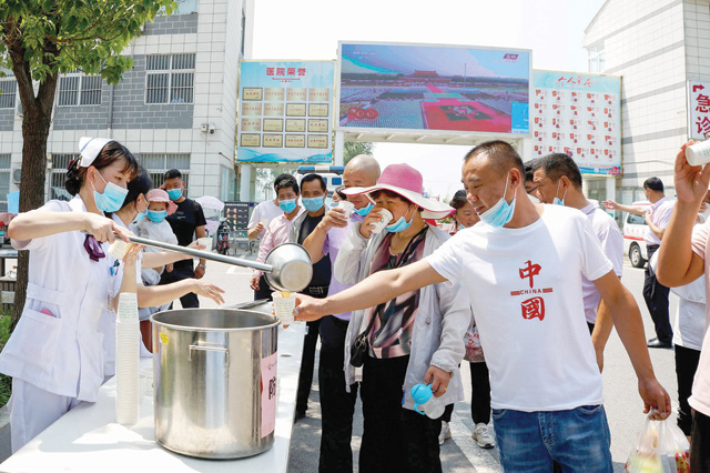 A staff member distributes free traditional Chinese medicine amid a rise in COVID-19 coronavirus cases across the country in Sihong, Suqian city, in China's eastern Jiangsu province on Sunday (AFP photo)