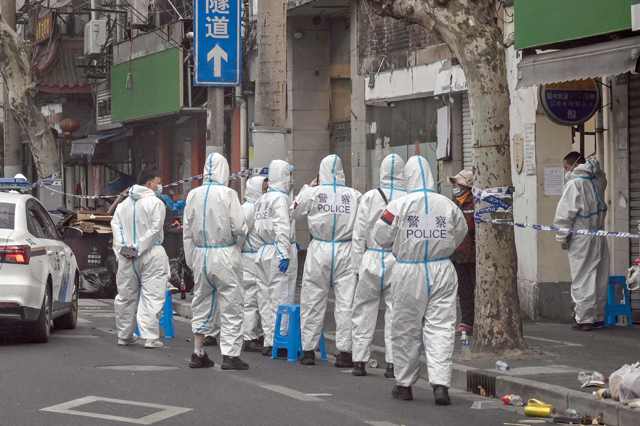 Police and workers are seen wearing protective clothes next to some lockdown areas after the detection of new cases of COVID-19 in Shanghai on Monday (AFP photo)