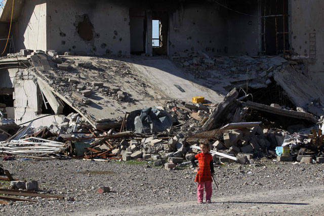 An Iraqi girl from the Shabak community walks past a damaged house, which was destroyed by the Daesh extremists, in the village of Baz Gerkan, east of Mosul, on January 10 (AFP photo)