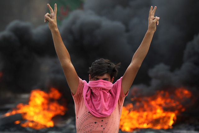 An Iraqi protester flashes the victory sign during a demonstration against state corruption, failing public services and unemployment in the Baladiyat district of the capital Baghdad on Wednesday (AFP photo)
