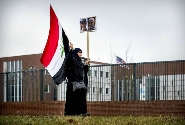 A protester holds an Iraqi flag and portraits of Iranian commander Qassem Soleimani (left) and Iraq's Hashed Al Shaabi deputy chief Abu Mahdi Al Muhandis as she protests outside the US embassy in The Hague on Tuesday (AFP photo)