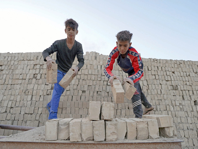 Iraqi labourers stack bricks at a factory in Iraq's central shrine city of Najaf on April 30 (AFP photo)
