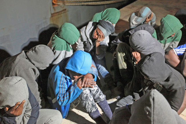 Migrants sit at a naval base after they were rescued by Libyan coastguard in Tripoli, Libya, on Tuesday (Reuters photo)