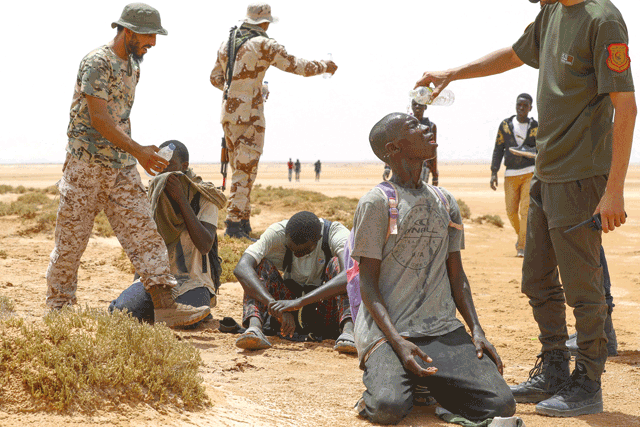 Libyan border guards provide water to migrants of African origin who reportedly have been abandoned by Tunisian authorities, following their arrival in an uninhabited area near Al Assah on the Libya-Tunisia border, on July 30 (AFP photo)