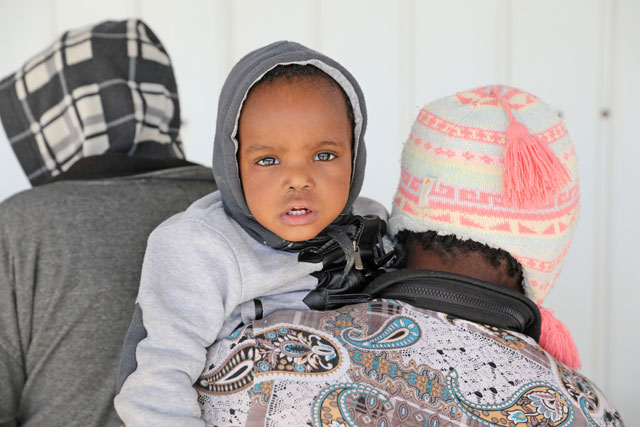 A migrant carries a child at a naval base after they were rescued by the Libyan coast guard in Tripoli, Libya, on Saturday (Reuters photo)