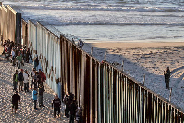 Central American migrants, moving towards the United States in hopes of a better life, stand by the US-Mexico border fence in Playas de Tijuana, Mexico, on Wednesday (AFP photo)
