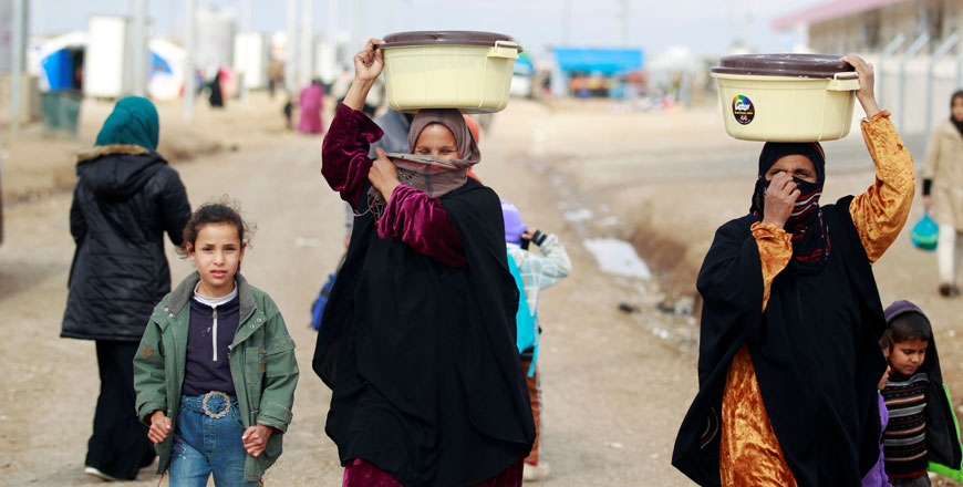 Displaced women, who fled the Daesh group stronghold of Mosul, carry plastic bowls in Khazer camp, Iraq, on Wednesday (Reuters photo)