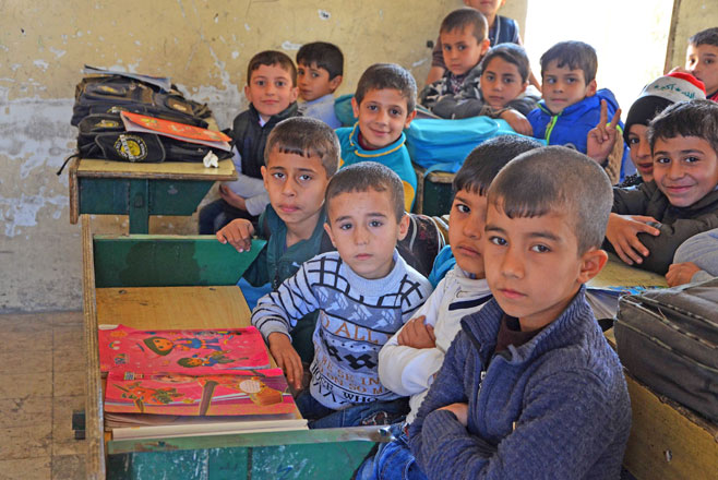 Iraqi children pose for a photo in a classroom in the battered city of Mosul on December 27, 2017 (AFP photo)