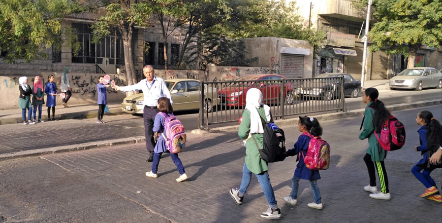 Mousa Zweiri is seen helping children cross the street in front of Al Batraa (Petra) school in Jabal Al Hussein, on Sunday (Photo by Fares Al Abed)
