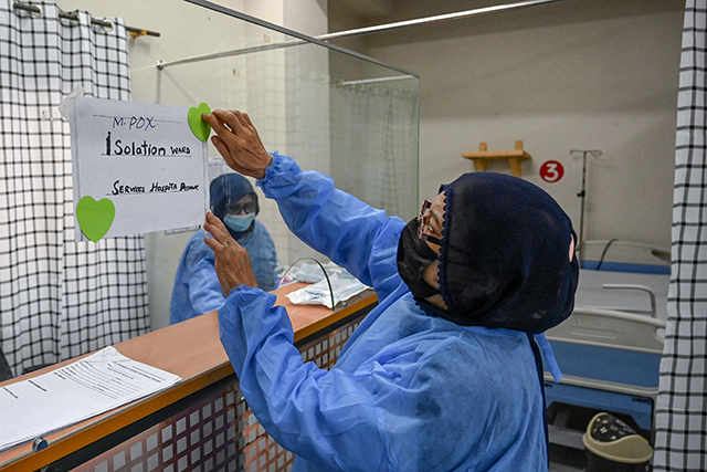 A health worker install a poster indicating an isolation ward prepared for mpox patients at the Police and Services hospital in Peshawar on August 20, 2024 (AFP photo)