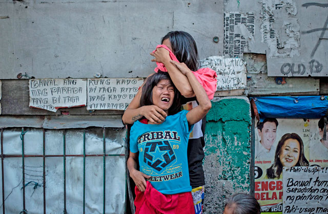 This photo taken on March 7 shows Analyn Roxas, 26, mourning with her sister after her partner, Valien Mendoza, a suspected drug dealer, was gunned down by unidentified assailants in Manila (AFP photo)
