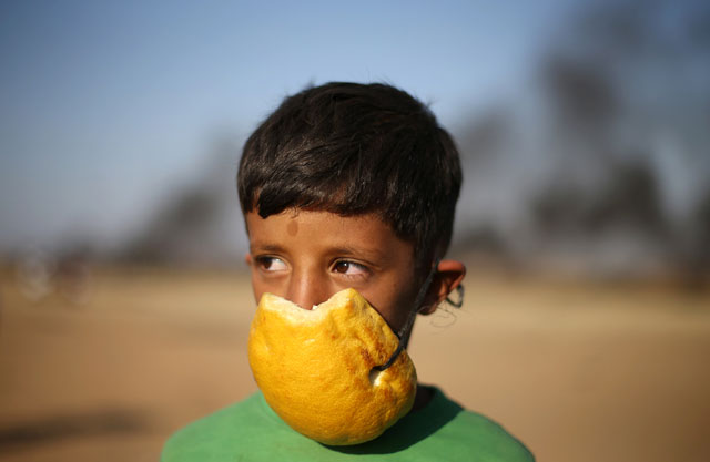 A Palestinian boy covers his nose with part of a pomelo to protect himself from inhaling tear gas fired by Israeli occupation forces during a protest at the Israel-Gaza border in the southern Gaza Strip on Monday (Reuters photo)