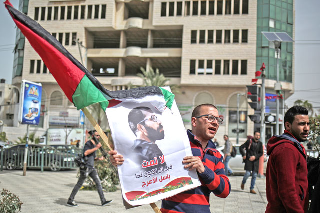 A protester holds a banner of Basil Al Aaraj as people gather to protest against Palestinian court’s trial on Basil Al Aaraj, who was killed during Israeli soldiers’ raid at his home in Ramallah (Anadolu Agency photo)