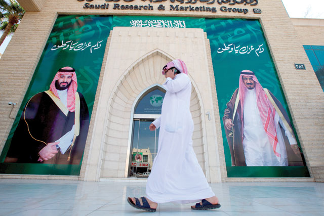 A man speaks on the phone as he walks past posters depicting Saudi Arabia's King Salman Bin Abdulaziz Al Saud and Crown Prince Mohammed Bin Salman in Riyadh, Saudi Arabia, on Thursday  (Reuters photo by Faisal Al Nasser)