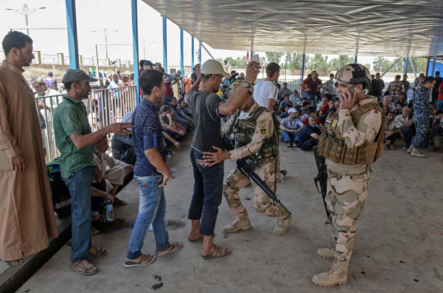 An Iraqi soldier frisks a displaced Iraqi man at a temporary camp in the compound of the closed Nineveh International Hotel in Mosul on Friday which was recovered by Iraqi troops from the Daesh group earlier in the year (AFP photo)