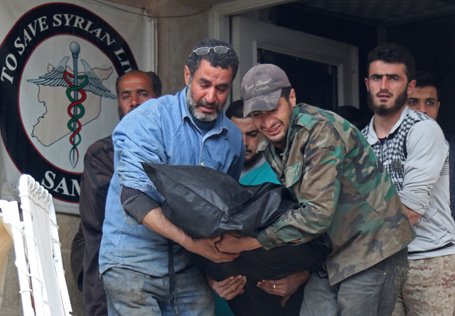 Syrians carry the body of a victim following reported strikes on an eastern neighbourhood of the village of Maaret Al Numan, in the country's northern province of Idlib, on Sunday (AFP photo)