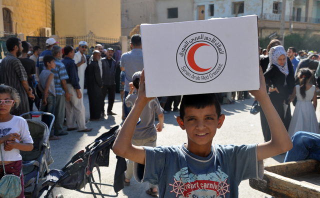 A Syrian child, resident of the northeastern city of Deir Ezzor, carries an aid parcel provided by the Syrian Red Crescent back on Friday (AFP photo)
