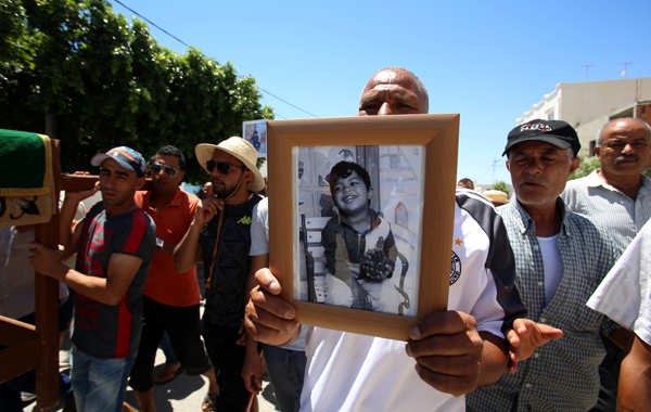 A man carries a picture of Kylan Mejri who died in the Nice attack in France, during a funeral in Enfidha, Tunisia, on Wednesday (Reuters photo)