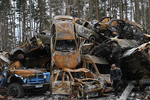 A man walks past destroyed and burned cars in Irpin on Tuesday, during the Russian invasion of Ukraine (AFP photo)