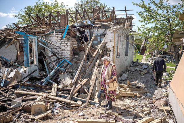 A couple brings their luggage out of their destroyed house in the village of Vilkhivka, near the eastern city of Kharkiv, on Saturday, on the 80th day of the Russian invasion of Ukraine (AFP photo)