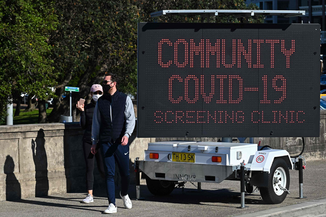 People walk past a sign for a COVID-19 testing clinic at Bondi Beach in Sydney on Saturday, on the first full day of a two-week coronavirus lockdown to contain an outbreak of the highly contagious Delta variant (AFP photo)