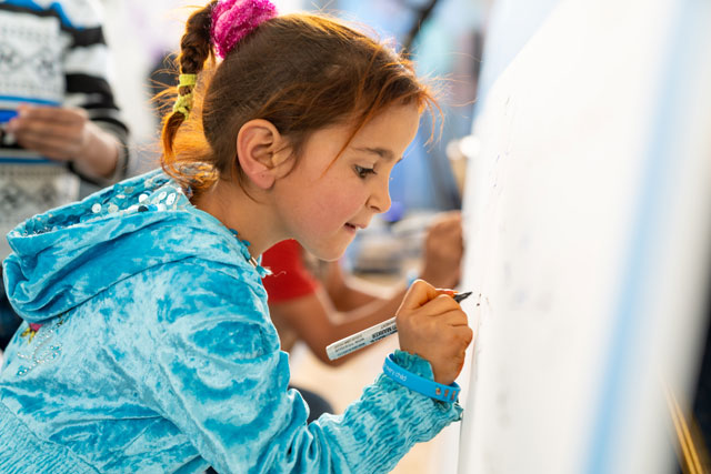 A young girl signs a global pledge calling on world leaders to commit to the rights of every child in Amman on Monday (Photo courtesy of UNICEF Jordan)