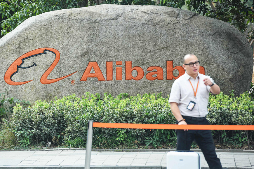 A staff member walks past a logo of Chinese e-commerce giant Alibaba in its headquarters in Hangzhou in China's eastern Zhejiang province on Friday (AFP photo)