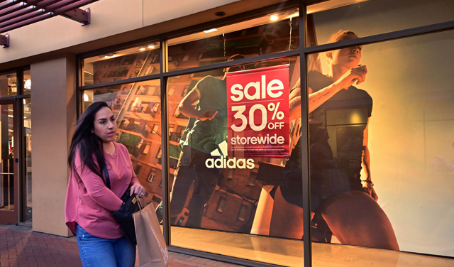 In this photo taken on May 21, 2019, a shopper at an outlet mall walks past an Adidas store in Los Angeles (AFP file photo)
