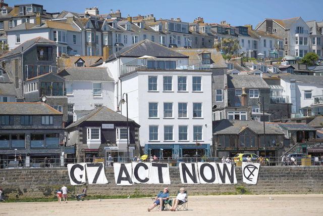 Extinction Rebellion environmental activists attach a banner calling on G-7 leaders to act on climate change on the beach in St Ives, Cornwall, during the G-7 summit on Sunday (AFP photo)