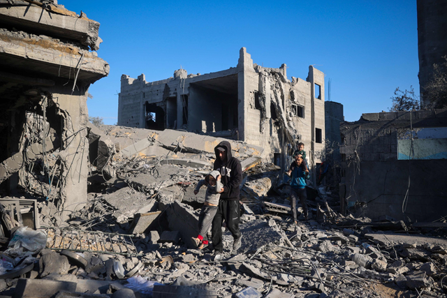 Men carry boys through the rubble of a house destroyed in an Israeli strike at the Nuseirat refugee camp, central Gaza Strip, on Tuesday (AFP photo)