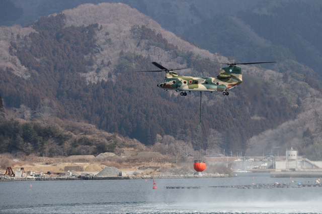 This handout photo taken yesterday  and received by AFP from Japan's Ministry of Defense today, shows a Ground Self-Defense Force helicopter picking up water as they fight a wildfire near the city of Ofunato, Iwate Prefecture (AFP photo)