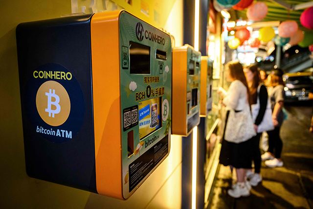 People stand next to bitcoin ATM's outside a cryptocurrency exchange in Hong Kong on Thursday (AFP photo)