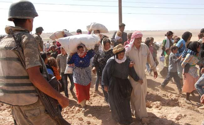 In this file photo, a Turkish soldier stands guard as Syrian refugees cross the border fence into Turkey in 2014 (Reuters photo)