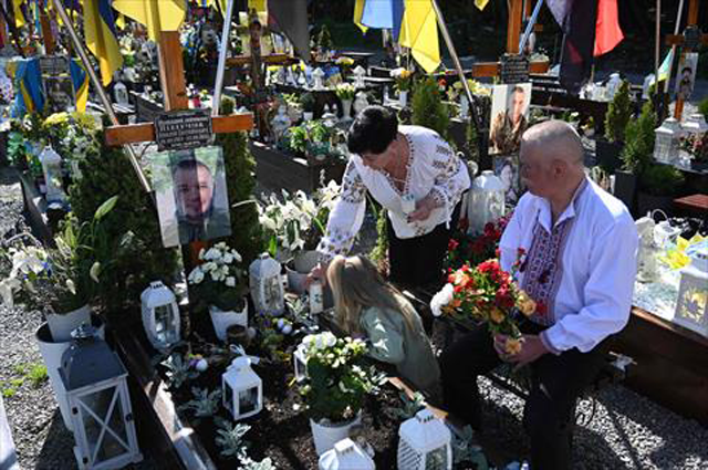 Members of a family lay flowers and candles as they mourn at a grave of a fallen Ukrainian soldier at the Lychakiv Military Cemetery on Easter Sunday in Lviv, on April 20, 2025, amid the Russian invasion of Ukraine (AFP photo)