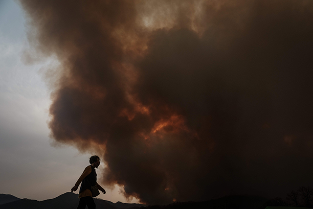 A woman walks as smoke from a wildfire fills the sky in Uiseong today (AFP photo)