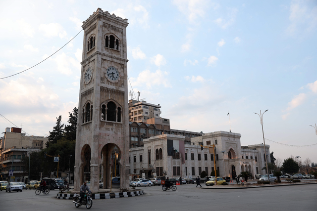 A man drives a bicycle past the landmark clock tower of the central Syrian city of Hama on January 27 (AFP photo)