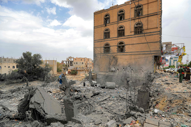 People gather by the rubble of a collapsed building at the site of a reported US air strike on Yemen's Huthi-held capital Sanaa yesterday (AFP photo)