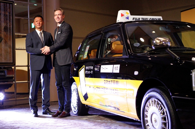 Uber Japan General Manager Tom White and Fuji Taxi Group President Hisashi Umemura (left) shake hands during a news conference in Nagoya, Japan, on Thursday (Reuters photo)