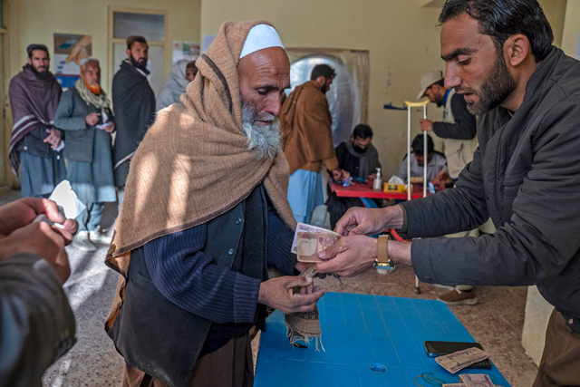 An Afghan man receives cash money being distributed as an aid by the World Food Programme organisation in Pul-i-Alam, the provincial capital of Logar Province on January 7, 2024 (AFP photo)